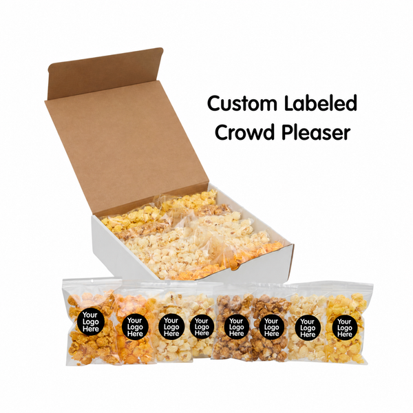 An open kraft cardboard box filled with assorted popcorn bags, with five clear sample bags displayed in front. The bags have black circular labels reading 'Your Logo Here.