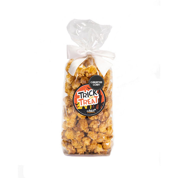 A clear plastic favor bag filled with caramel corn, sealed with a white twist tie, and adorned with a 'Trick or Treat' label for Halloween.
