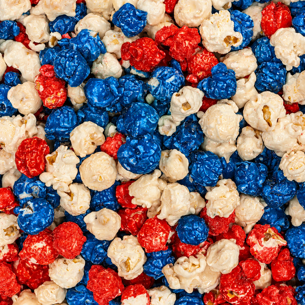 A close-up, top-down view of popcorn kernels in red, blue, and white candy coating, arranged in a pattern reminiscent of the American flag.
