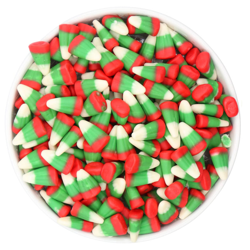 Assorted red, green, and white candy corn in a white bowl on a white background